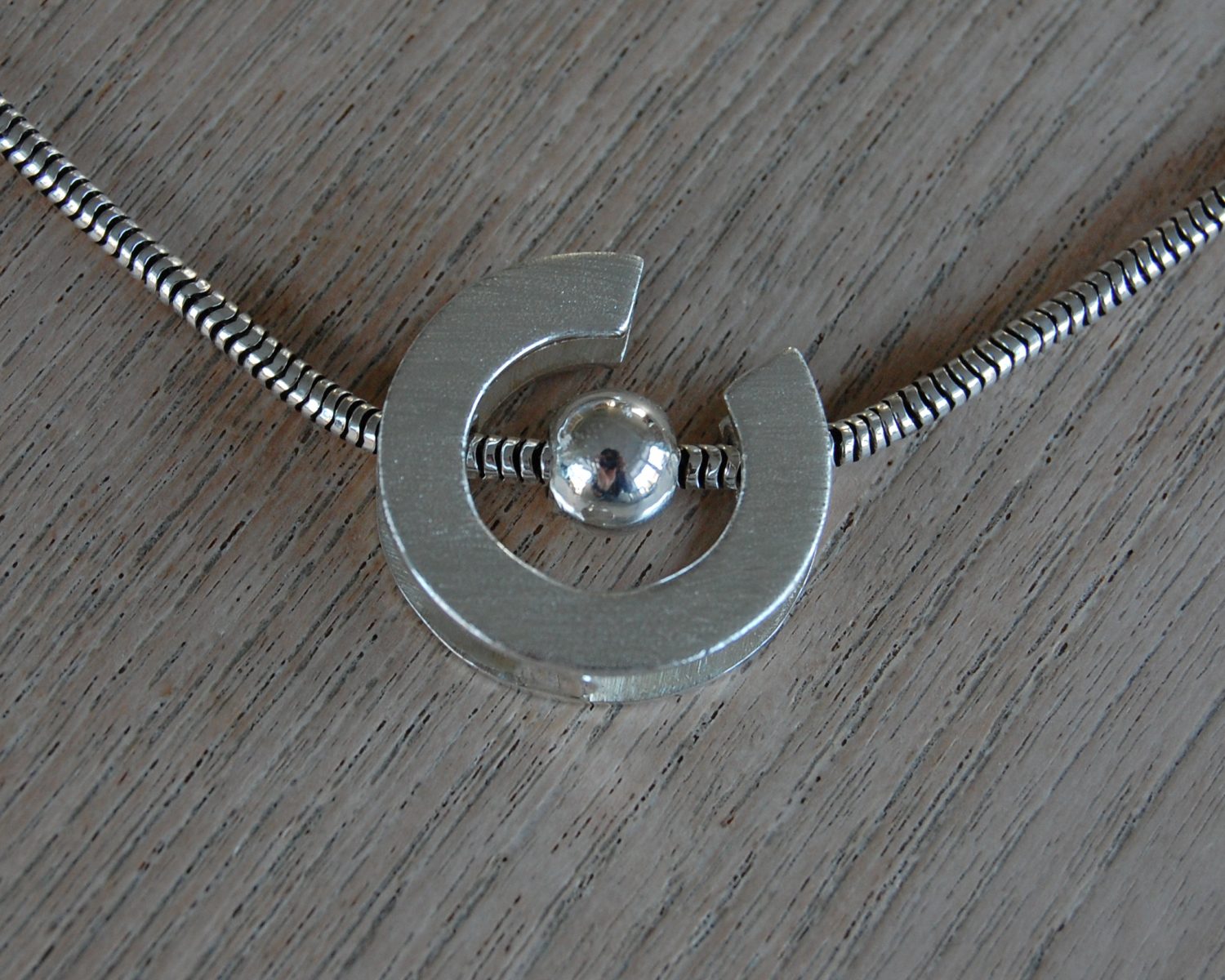 Hanger in zilver. In een buisje onder in de hanger is wat as opgeslagen.