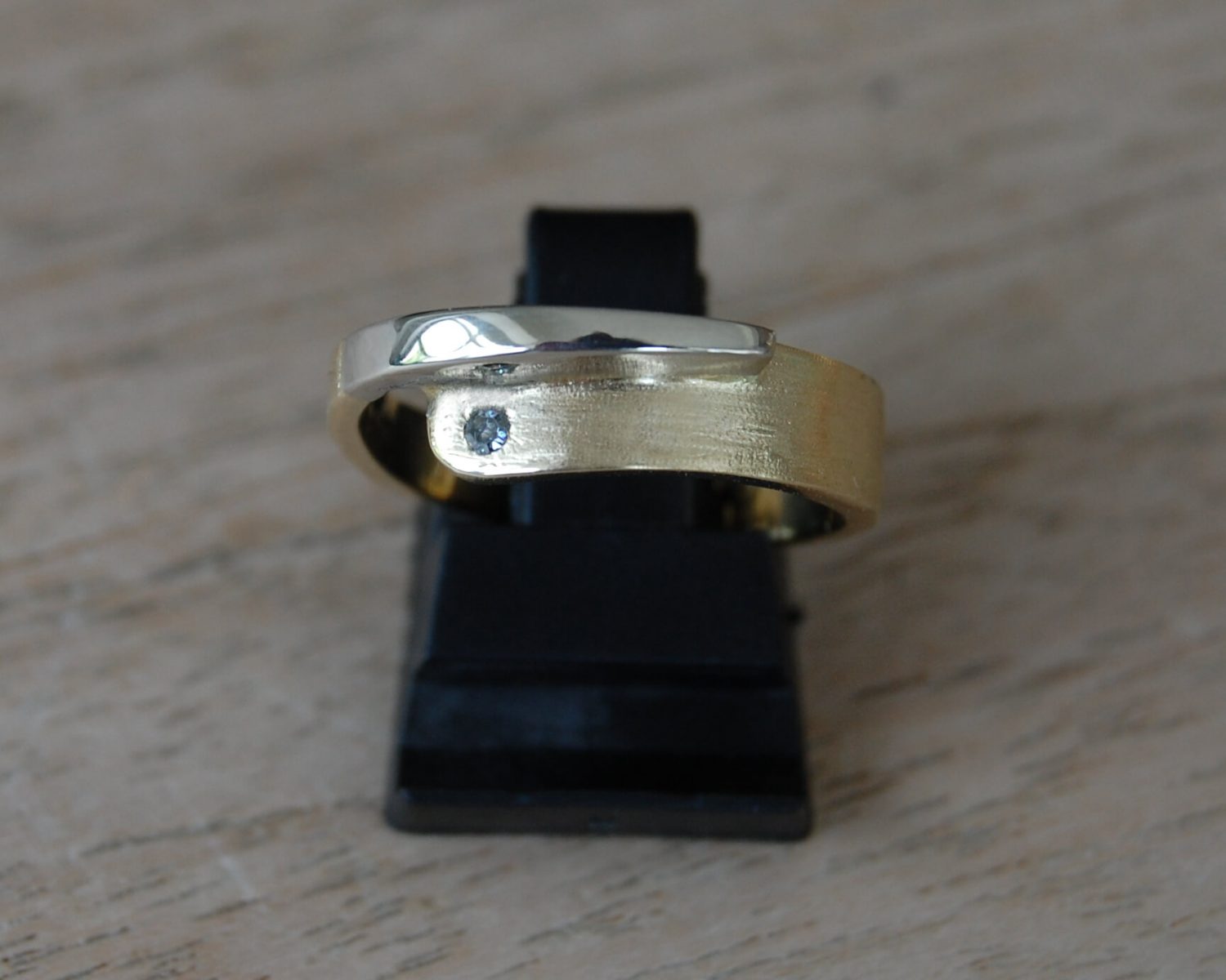 Ring gemaakt uit aangeleverd geelgoud en toegevoegd witgoud - inclusief diamant van 0,02 karaat. Aan de binnenzijde van de ring is een bakje gemaakt, gevuld met wat as.