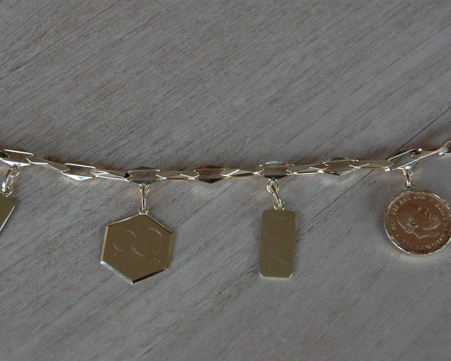 Aan een bestaande closed-for-ever armband zijn twee nieuwe bedels uit aangeleverde gouden sieraden gemaakt.