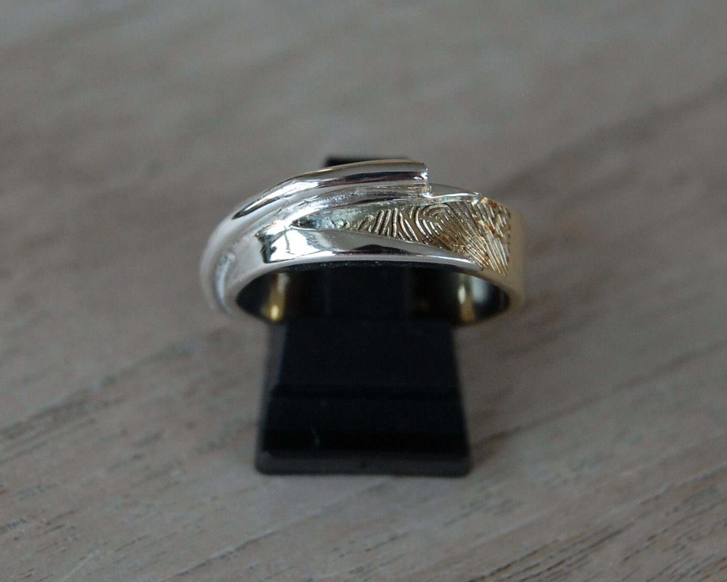 Ring gemaakt uit een aangeleverde trouwring. In het zilveren buisje is as gezet en een vingerafdruk is in het goud gelaserd.