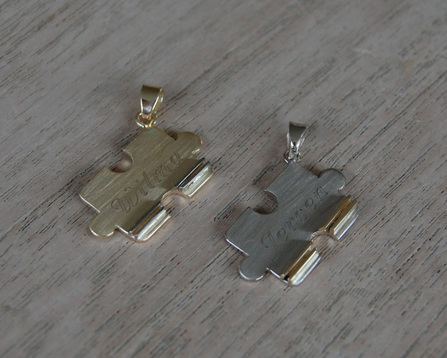 Symbolische hangers uit aangeleverd geelgoud en toegevoegd witgoud - inclusief gravure.