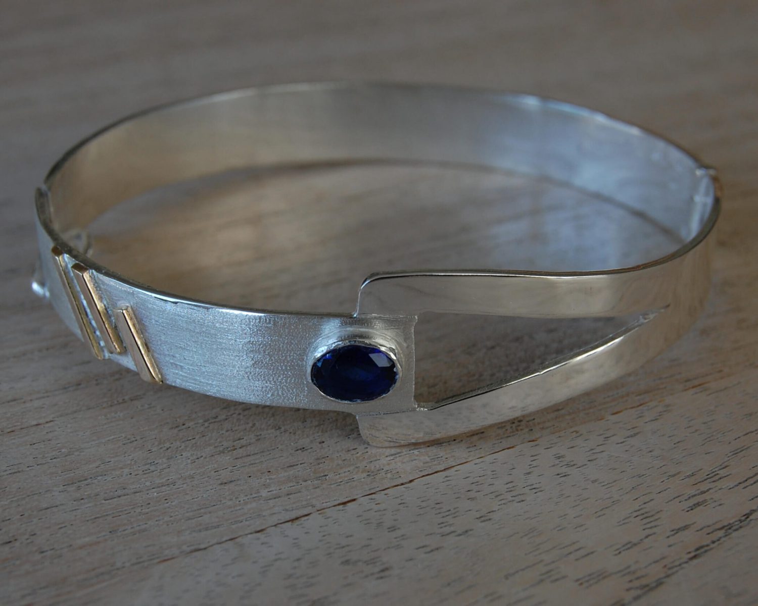 Symbolische armband gemaakt uit deels aangeleverd zilver en accenten uit aangeleverd goud - inclusief opnieuw gezette saffier.